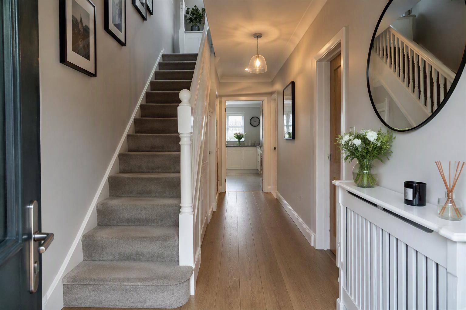 Clean, bright hallway with stairs and wooden floor